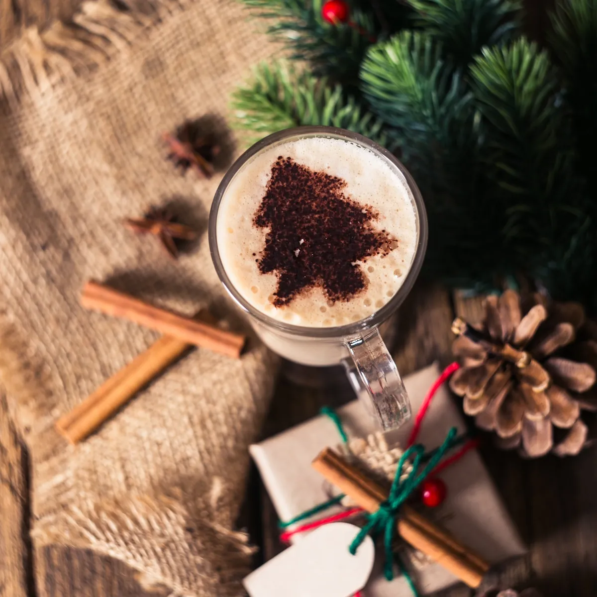 Tasse Kaffee mit Zimtstange und Tannenzweig auf einem Holztisch