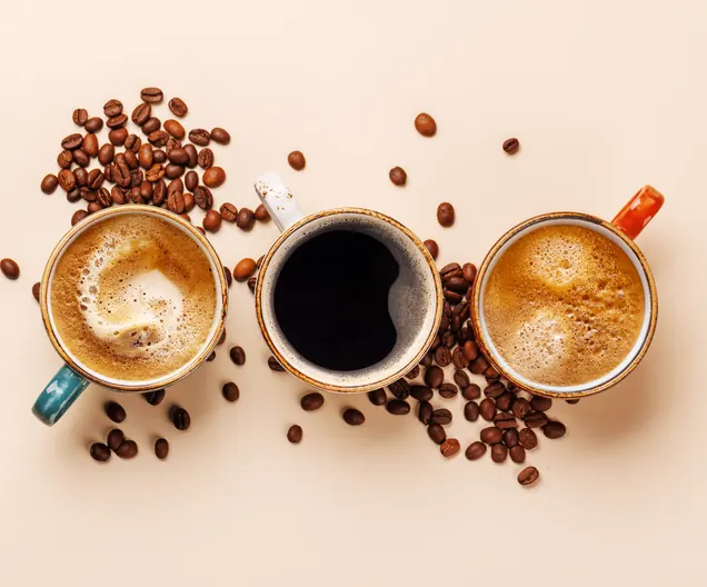 Drei Tassen Kaffee mit Kaffeebohnen von oben