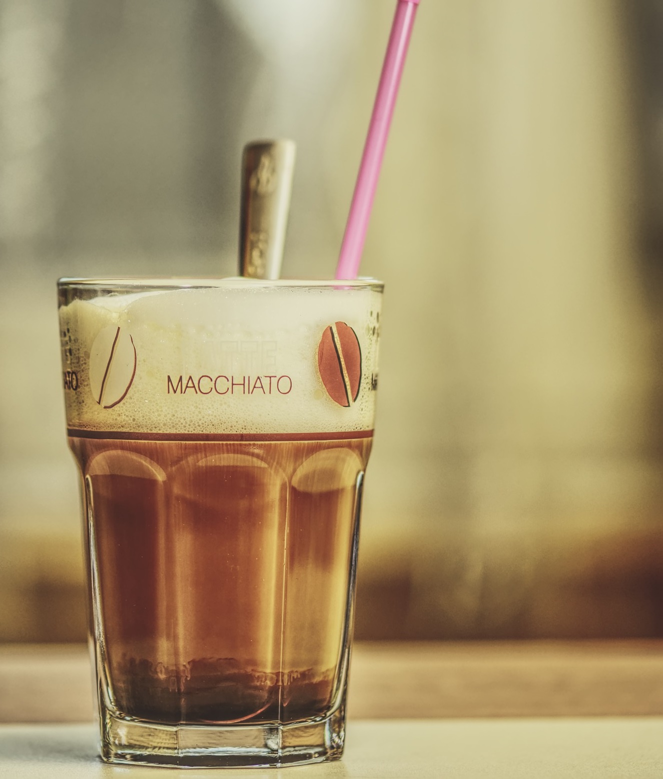 glas mit latte macchiato und pinkem Strohhalm