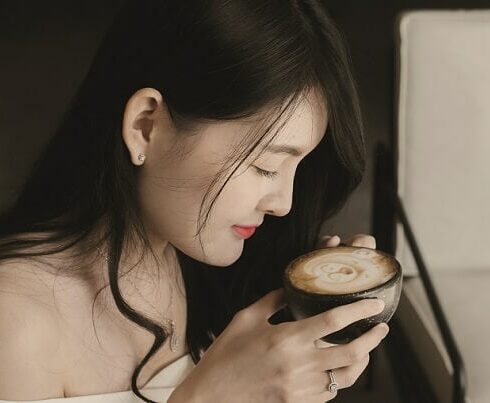 asiatische Frau beugt sich über Kaffeetasse
