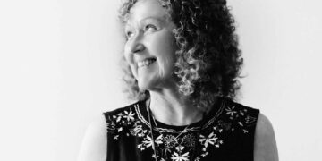 Frau mit lockigem Haar blickt auf schwazr-weiß Foto lachend nach links