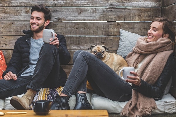 junger mann und junge Frau trinken auf Couch kaffee mit Hund