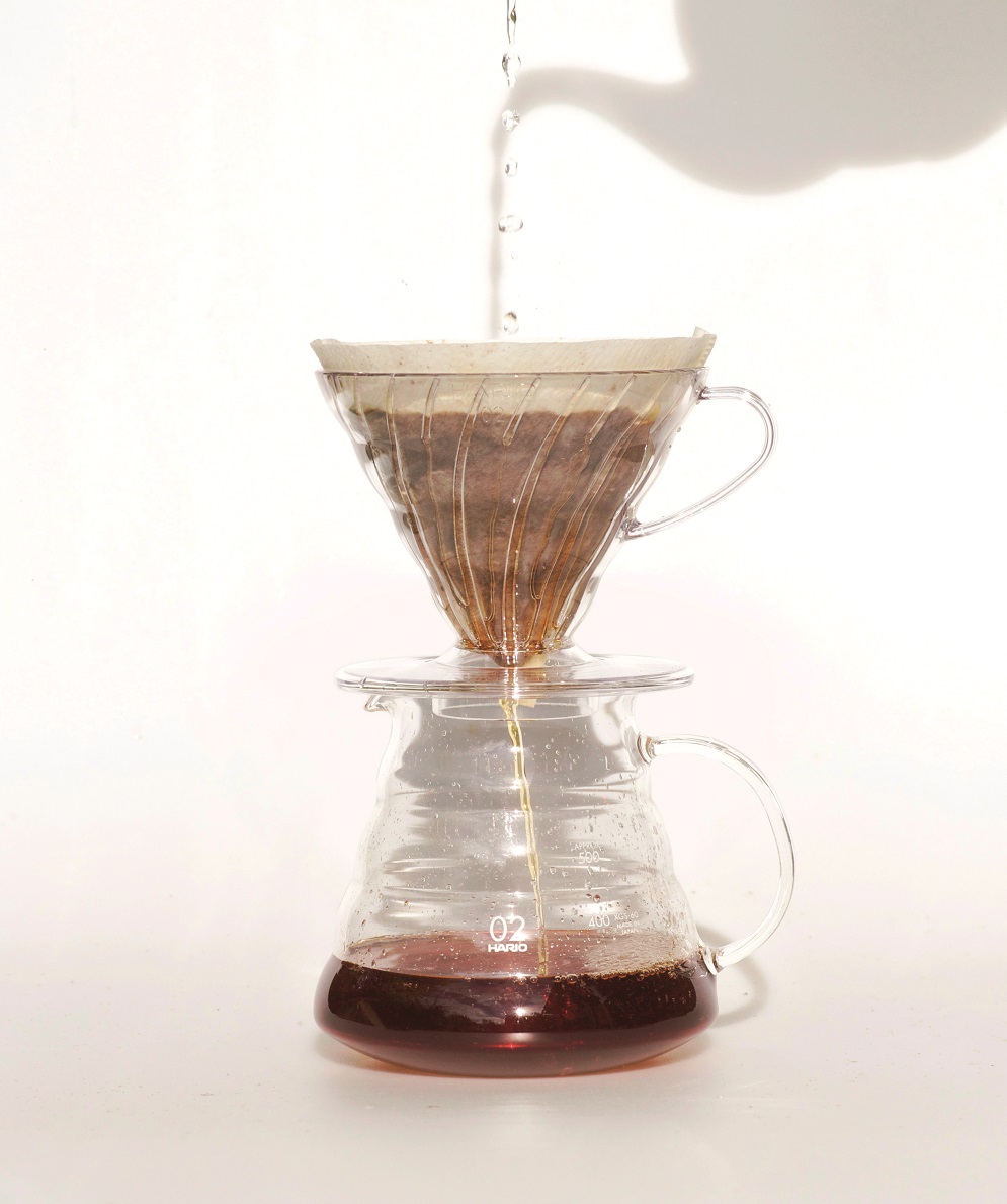 Glaskaffee  mit Kaffeefilter und Kaffee und Wasserstrahl von oben