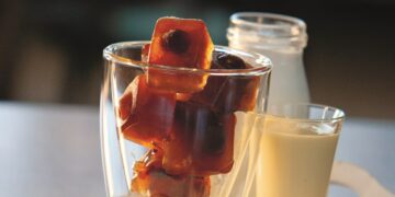 Glas mit Kaffeeeiswuerfel und Glas mit Vanillesoße und Milch daneben