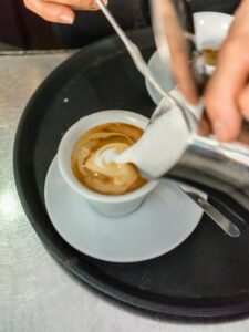 barista pouring milk in cappuccino