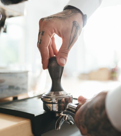 Close up barista hands preparing making coffee in coffee shop
