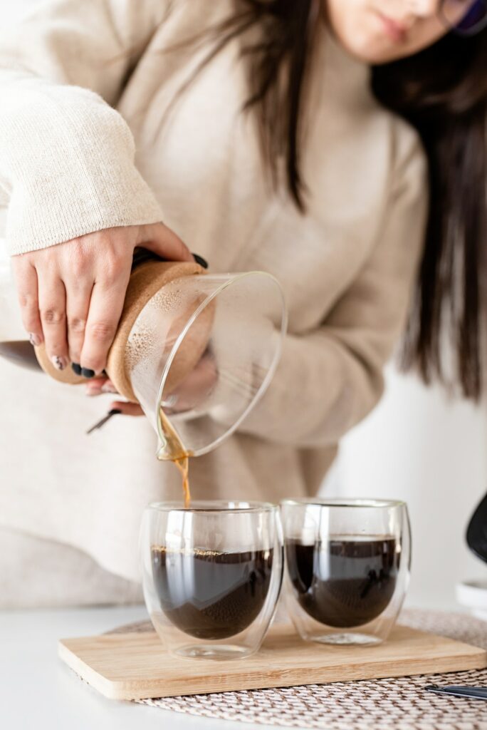 Young woman brewing coffee in chemex, pouring coffee to the glass