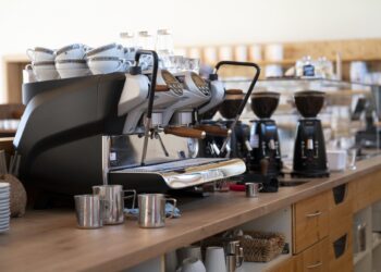 Espressomaschine auf Theke mit Tassen, Glaesern und Kaffeemuehlen