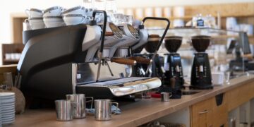 Espressomaschine auf Theke mit Tassen, Glaesern und Kaffeemuehlen