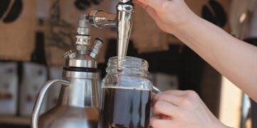 Zapfanlage, aus der in ein Glas von einer Hand Cold Brew eingelassen wird