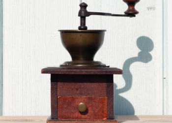 alte dunkelbraune Kaffeemuhele aus Holz vor heller Holzwand