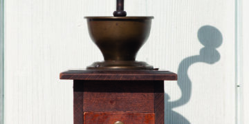 alte dunkelbraune Kaffeemuhele aus Holz vor heller Holzwand