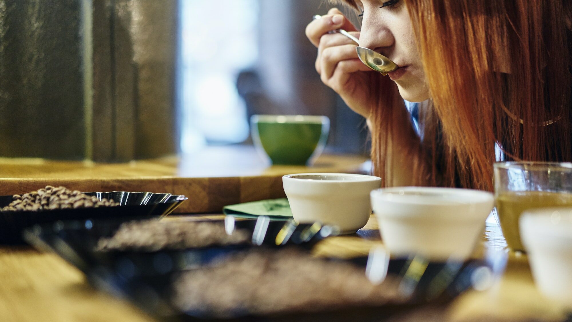 Close up woman tasting bowls of coffee at coffee shop tasting