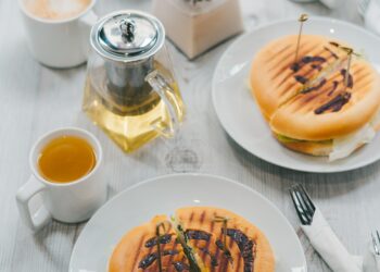 Table breakfast or dinner at window in cafe with panini, tea and coffee, food lifestyle