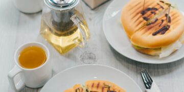 Table breakfast or dinner at window in cafe with panini, tea and coffee, food lifestyle