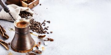 Turkish coffee brewing pot and beans on concrete with copy space