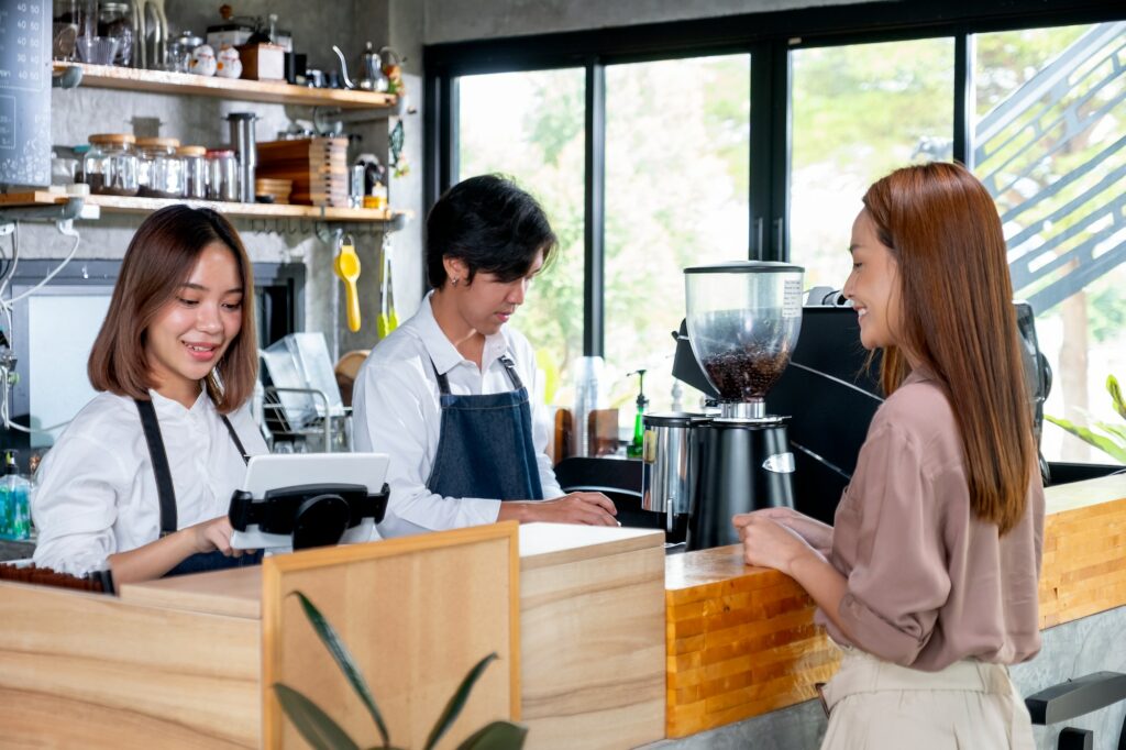 Asian barista or coffee maker receive the order from customer woman