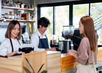 Asian barista or coffee maker receive the order from customer woman