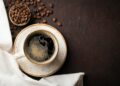 Close-up of a Cup of black coffee and coffee beans on a dark background. Top view with copy space