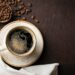 Close-up of a Cup of black coffee and coffee beans on a dark background. Top view with copy space