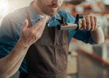 Close up of barista inhaling the aroma of coffee in own manufacturing of roasted coffee