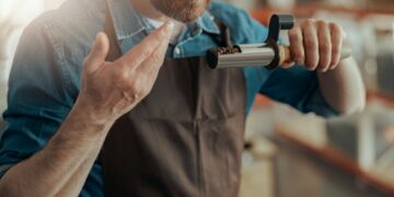 Close up of barista inhaling the aroma of coffee in own manufacturing of roasted coffee