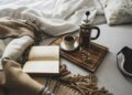 Coffee brewed in a French press and a cup on a wooden board with open book in bed.