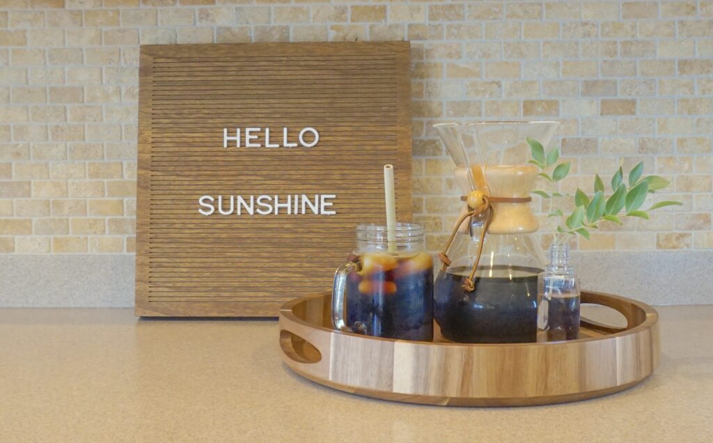Cold brew iced coffee on a wooden tray and hello sunshine on a wooden message board