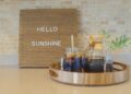 Cold brew iced coffee on a wooden tray and hello sunshine on a wooden message board