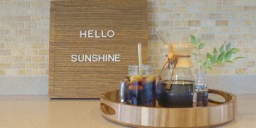 Cold brew iced coffee on a wooden tray and hello sunshine on a wooden message board