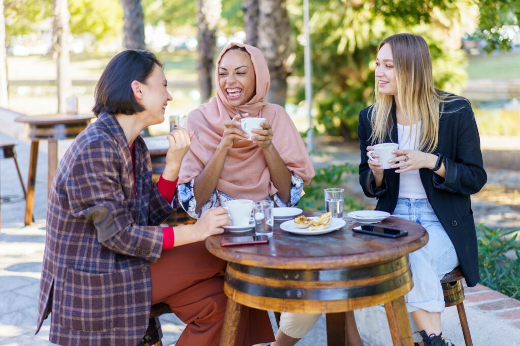 Delighted diverse women drinking coffee