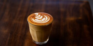 Glass of flat white coffee with heart shaped foam milk