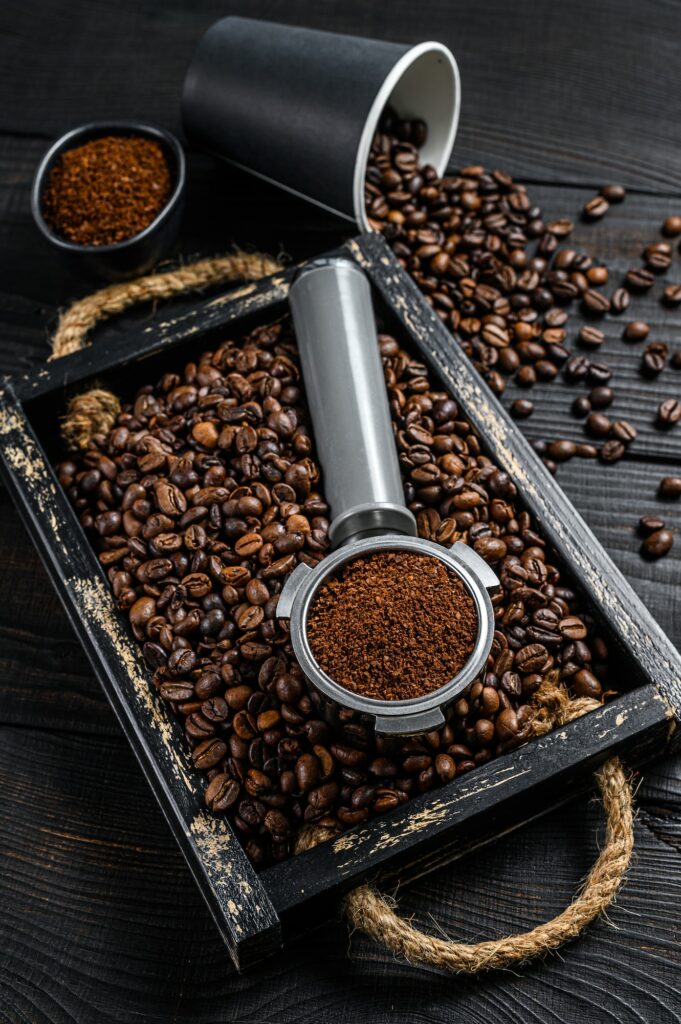 Ground Coffee in Portafilter for Espresso in a wooden tray with coffee beans.