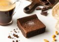selective focus of delicious brownie piece near coffee on white background