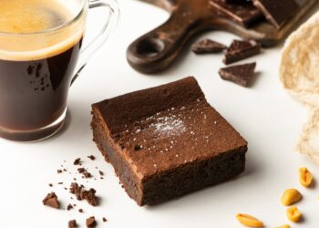 selective focus of delicious brownie piece near coffee on white background