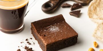 selective focus of delicious brownie piece near coffee on white background