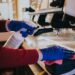 Woman cleaning the coffee machine with sanitizer and towel with blue gloves put on