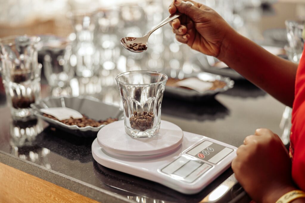 Woman spooning coffee beans into a glass on the scales