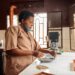 African American woman in face mask stacking coffee beans in a bowl