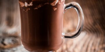 Chocolate coffee with whipped cream on wooden background