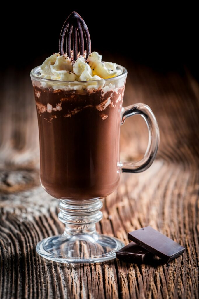 Chocolate coffee with whipped cream on wooden background
