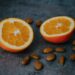 Closeup of sliced oranges and almond nuts on a gray surface