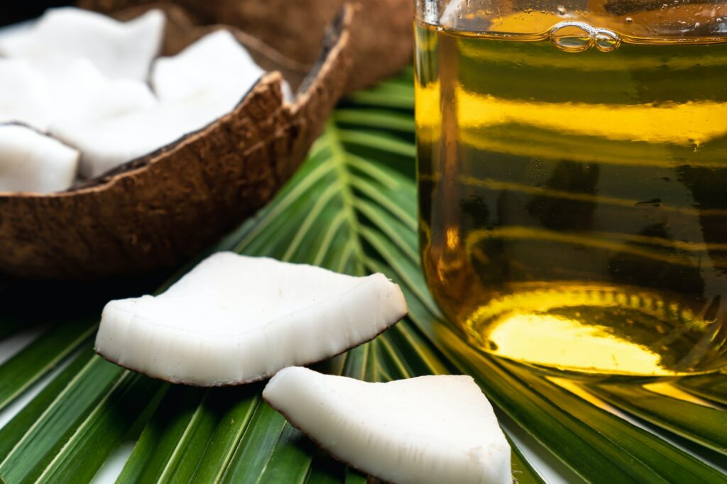 Coconut meat and coconut oil in glass bottle on coconut leaf.