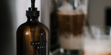 coffee espresso machine on kitchen counter with glass of iced coffee drinks and syrup pump bottle