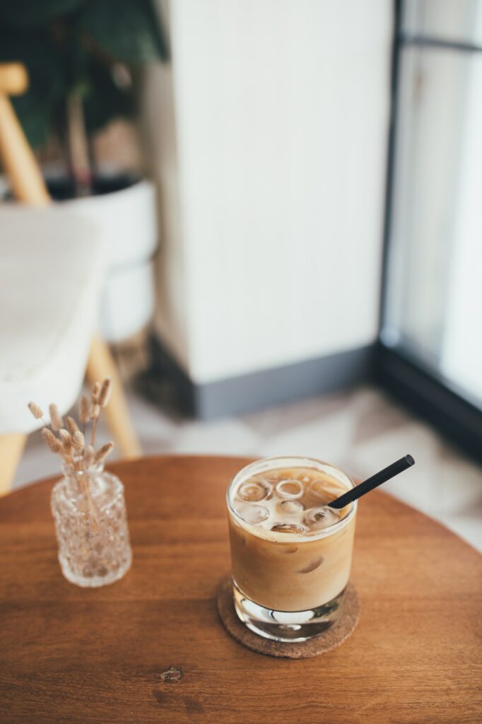 Fresh iced coffee with a straw on wooden table.