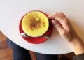 Hand holding a cup with a Tumeric latte