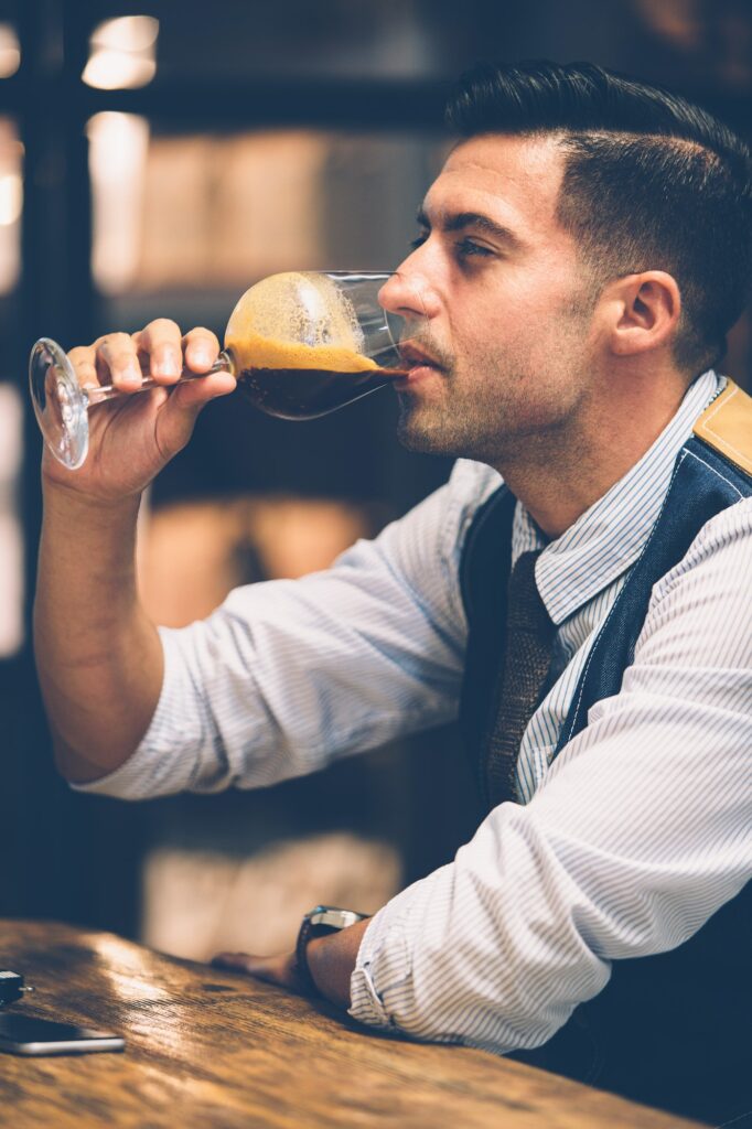 Handsome man drinking coffee from wine glass
