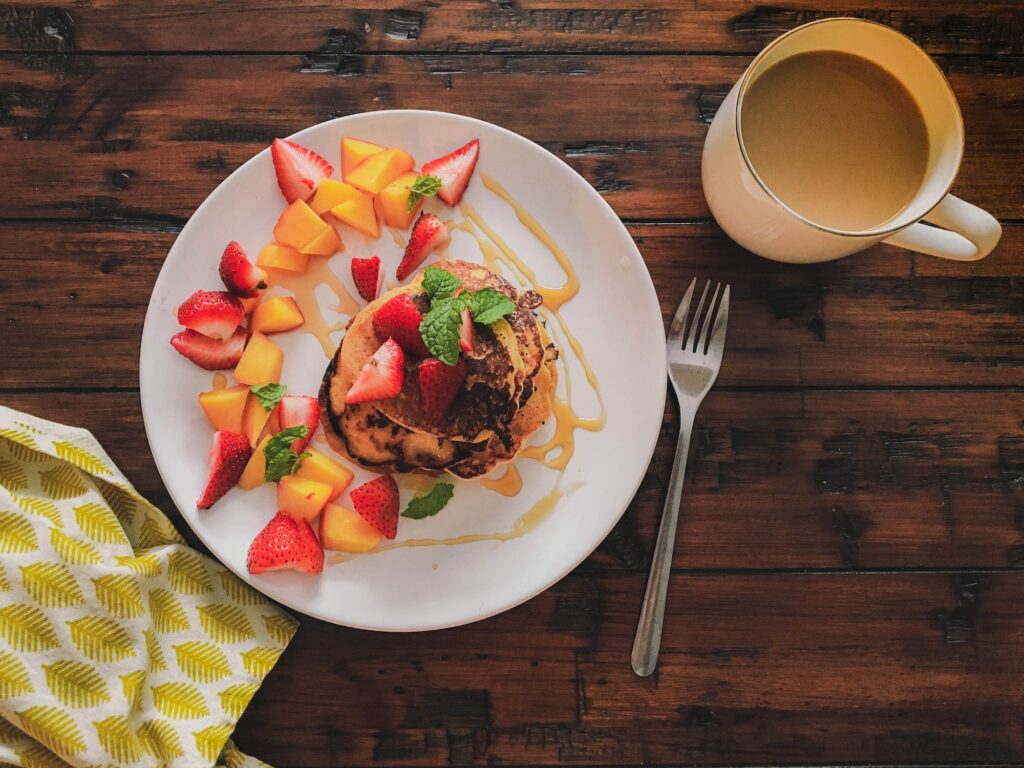 Homemade pancakes with fruit a cup of coffee with milk.