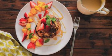 Homemade pancakes with fruit a cup of coffee with milk.