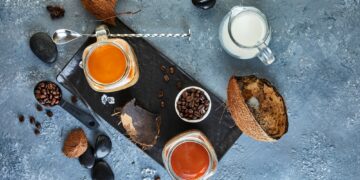 Ice coffee in Thai style with coconut milk and coffee beans on gray-blue background.